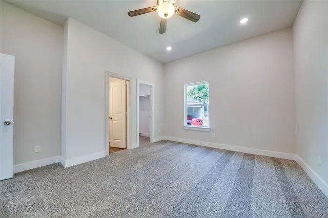 an empty room with windows and ceiling fan