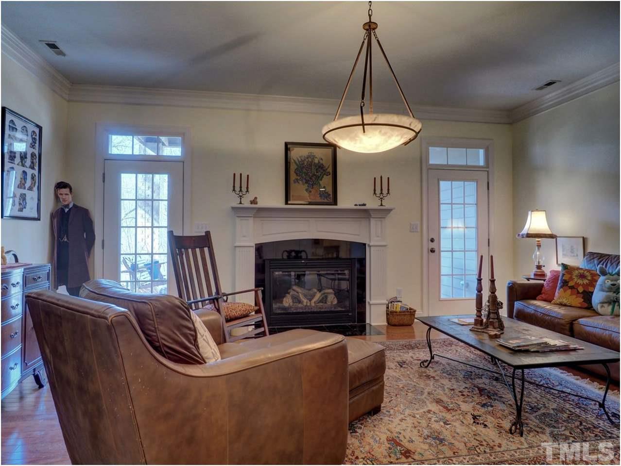 3408 Ocotea Street Raleigh, NC 27607 - Photo 19 of 25 a living room with furniture a chandelier and a fireplace