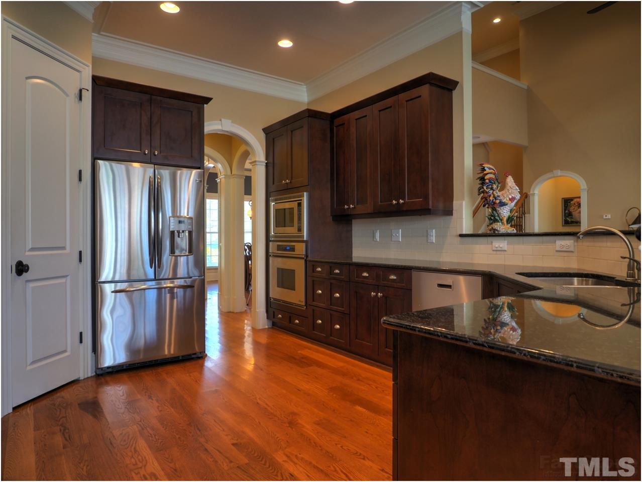 3408 Ocotea Street Raleigh, NC 27607 - Photo 9 of 25 a kitchen with stainless steel appliances granite countertop a refrigerator a stove and a sink with wooden floor