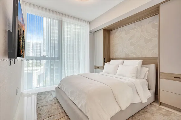 a large bed sitting in a bedroom next to a window