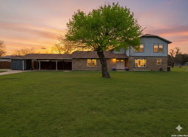 a view of a house next to a big yard and large trees