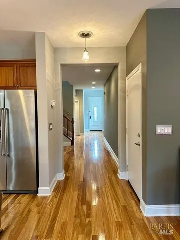 a view of a hallway with wooden floor and a refrigerator