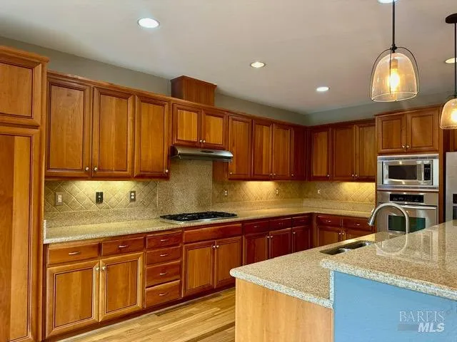 a kitchen with kitchen island granite countertop a sink stainless steel appliances and cabinets