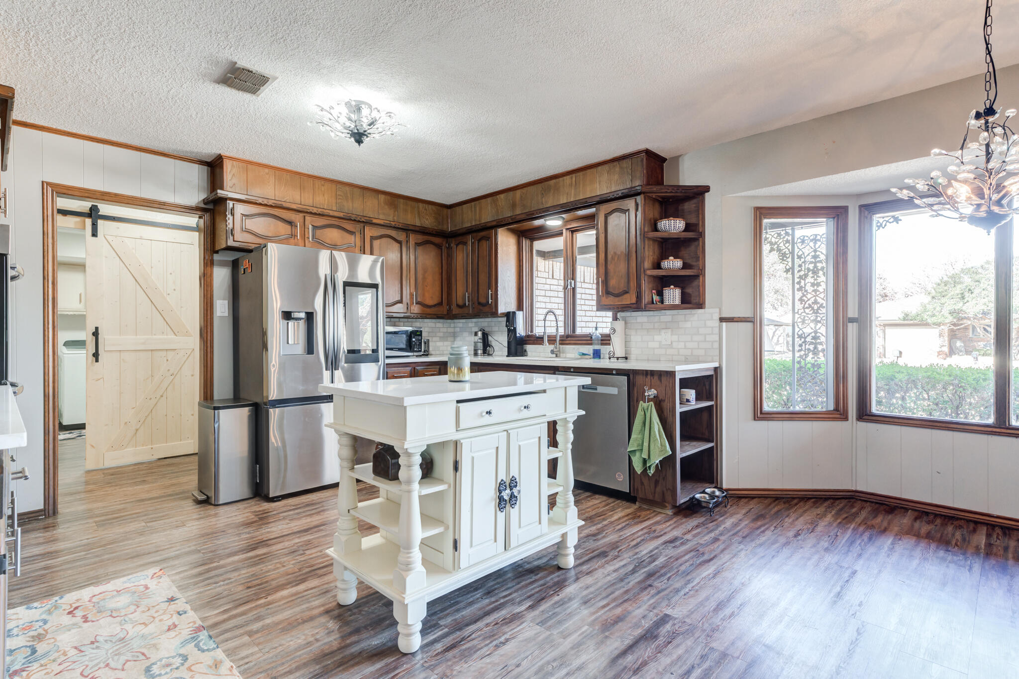5703 80th Street Lubbock, TX 79424 - Photo 20 of 45 a kitchen with a refrigerator a sink cabinets and wooden floor