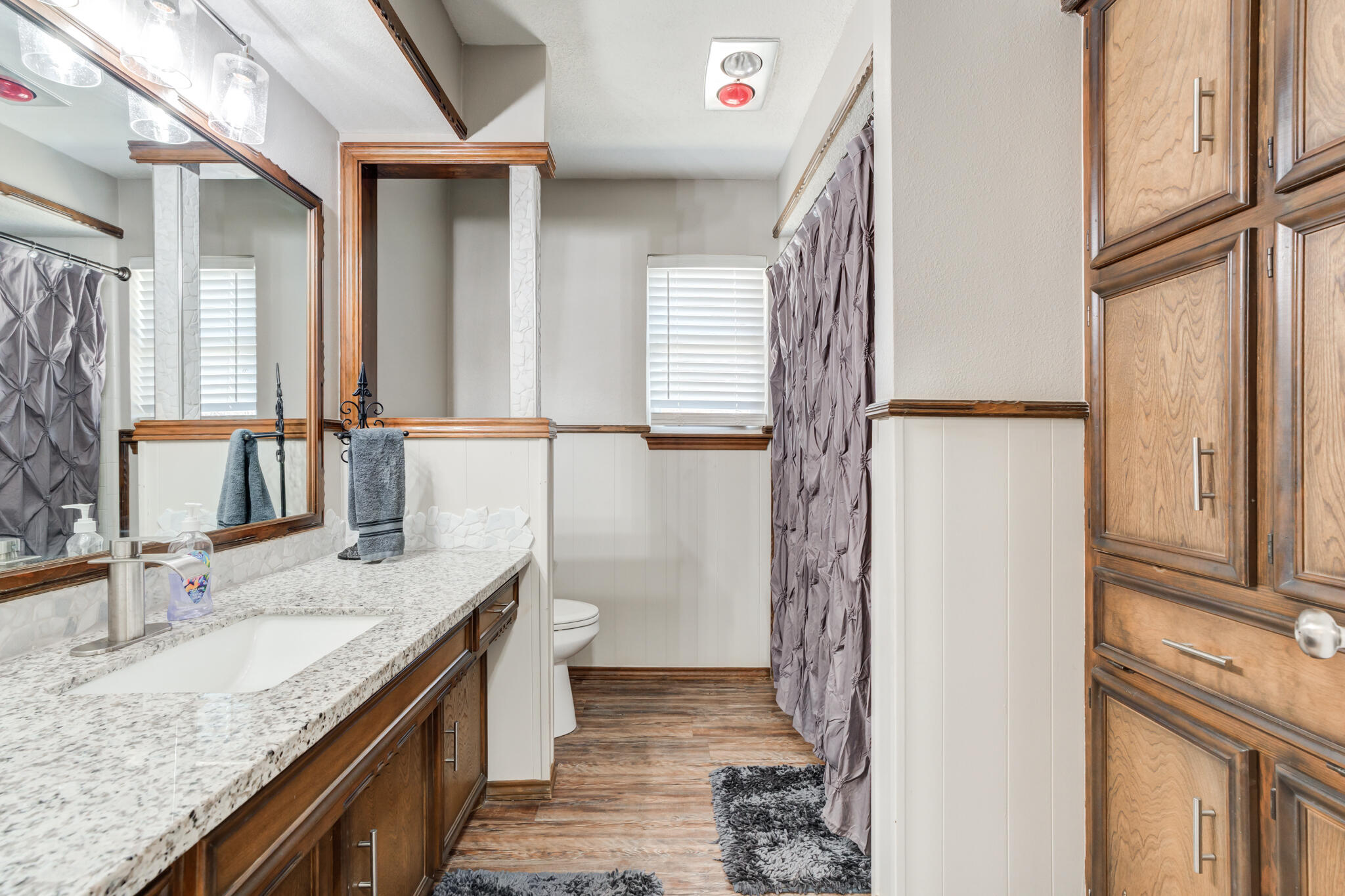 5703 80th Street Lubbock, TX 79424 - Photo 7 of 45 a bathroom with a granite countertop sink a mirror and a shower