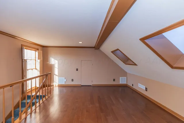 a view of staircase with lots of frames on wall and wooden floor