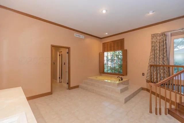 an empty room with a bathroom and a chandelier fan