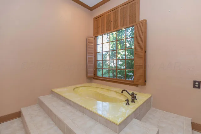 an empty room with a chandelier fan and windows