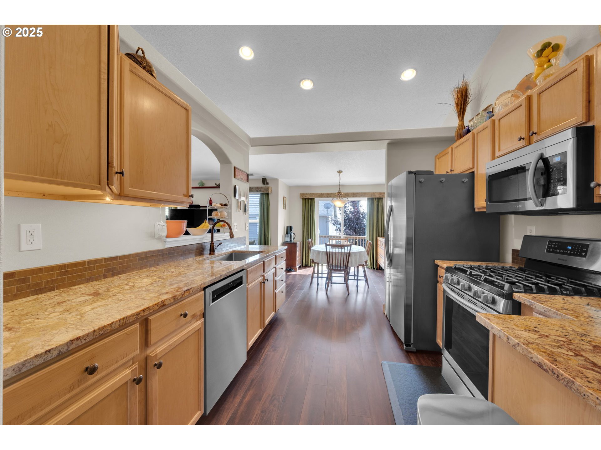 6057 Pebble Court Springfield, OR 97478 - Photo 15 of 42 a kitchen with stainless steel appliances kitchen island granite countertop a stove a sink a refrigerator and wooden cabinets with wooden floor