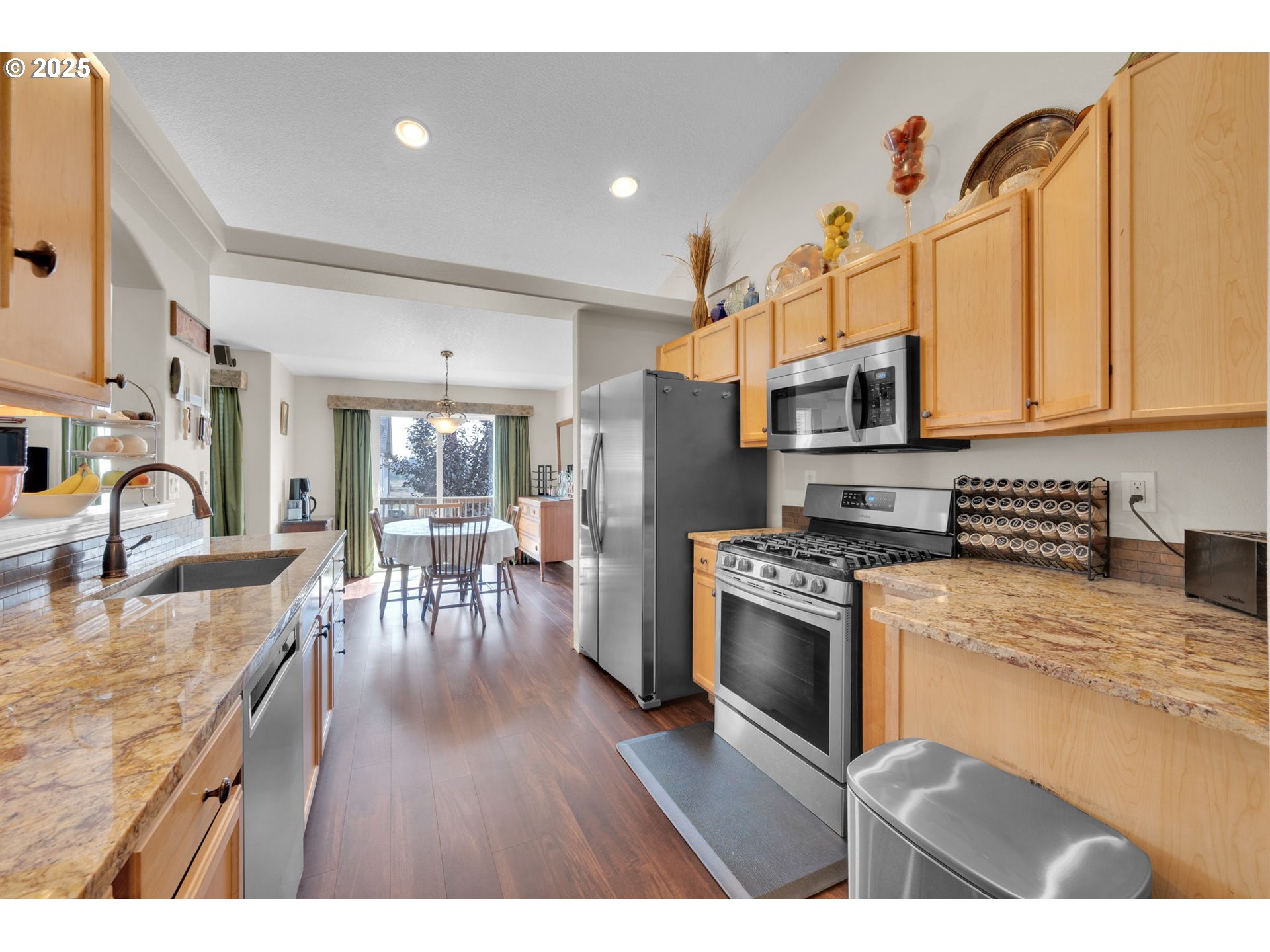6057 Pebble Court Springfield, OR 97478 - Photo 16 of 42 a kitchen with stainless steel appliances granite countertop a refrigerator a stove top oven a sink dishwasher and white cabinets with wooden floor