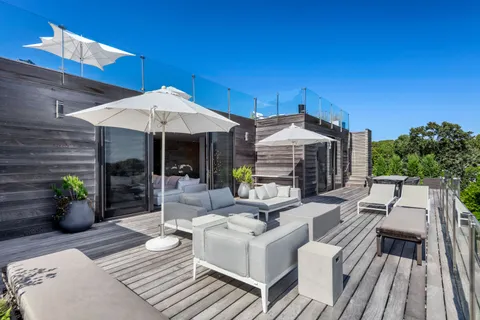 a view of a patio with couches table and chairs under an umbrella