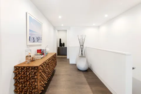 a hallway with a white couches and chairs with wooden floor