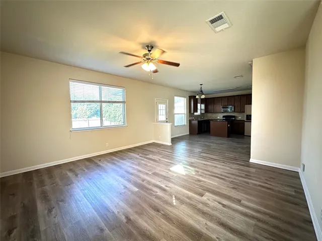 a view of a kitchen with wooden floor a ceiling fan and windows