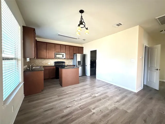 a kitchen with stainless steel appliances granite countertop a refrigerator a sink dishwasher a stove and a refrigerator with wooden floor