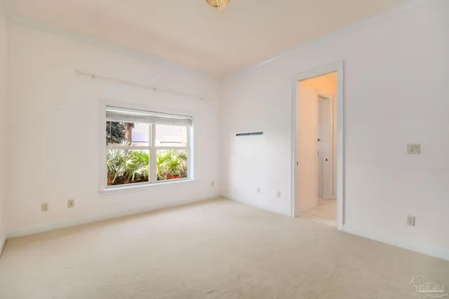 a view of an empty room with a chandelier fan and windows