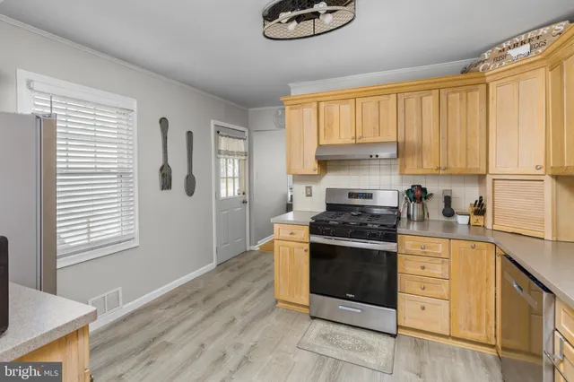 a kitchen with stainless steel appliances granite countertop a refrigerator a stove and a dining table with wooden floor