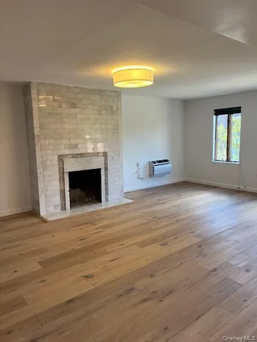 a view of empty room with wooden floor and fireplace