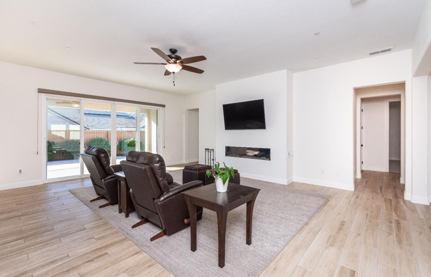 124 Basile Court Lincoln, CA 95648 - Photo 15 of 55 living room with ceiling fan, light wood finished floors, and a glass covered fireplace
