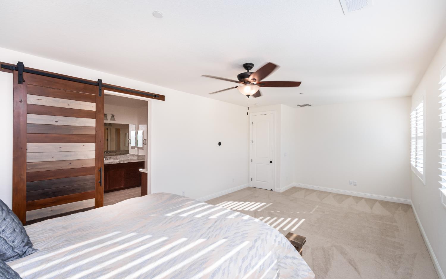124 Basile Court Lincoln, CA 95648 - Photo 21 of 55 unfurnished bedroom with a barn door, ensuite bath, light colored carpet, and a ceiling fan