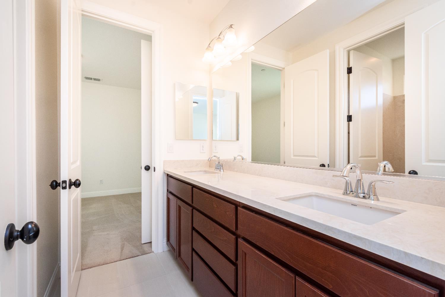 124 Basile Court Lincoln, CA 95648 - Photo 29 of 55 full bathroom with double vanity, light colored carpet, and light tile patterned floors