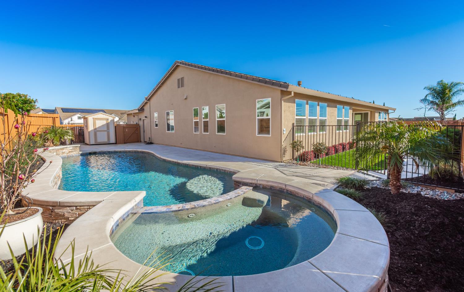 124 Basile Court Lincoln, CA 95648 - Photo 6 of 55 back of house with a storage unit, a fenced backyard, a pool with connected hot tub, a patio area, and stucco siding