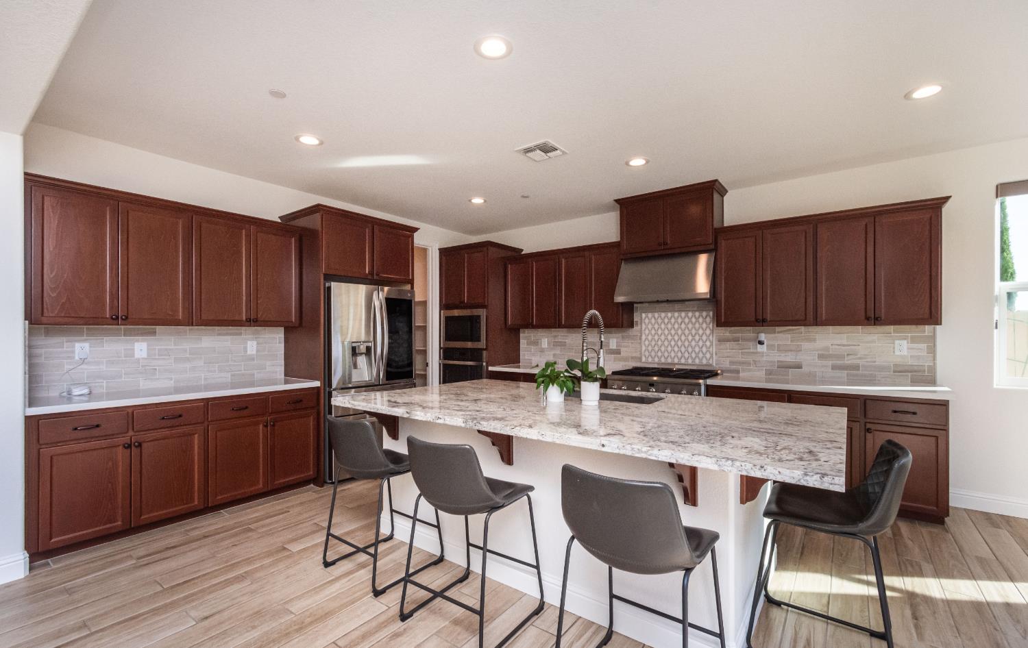 124 Basile Court Lincoln, CA 95648 - Photo 8 of 55 kitchen featuring a breakfast bar, light stone countertops, a center island with sink, light wood-type flooring, and stainless steel appliances