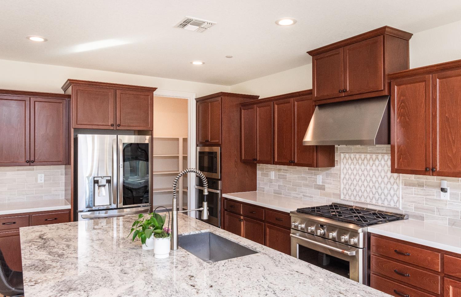 124 Basile Court Lincoln, CA 95648 - Photo 10 of 55 kitchen with stainless steel appliances, extractor fan, decorative backsplash, light stone countertops, and recessed lighting