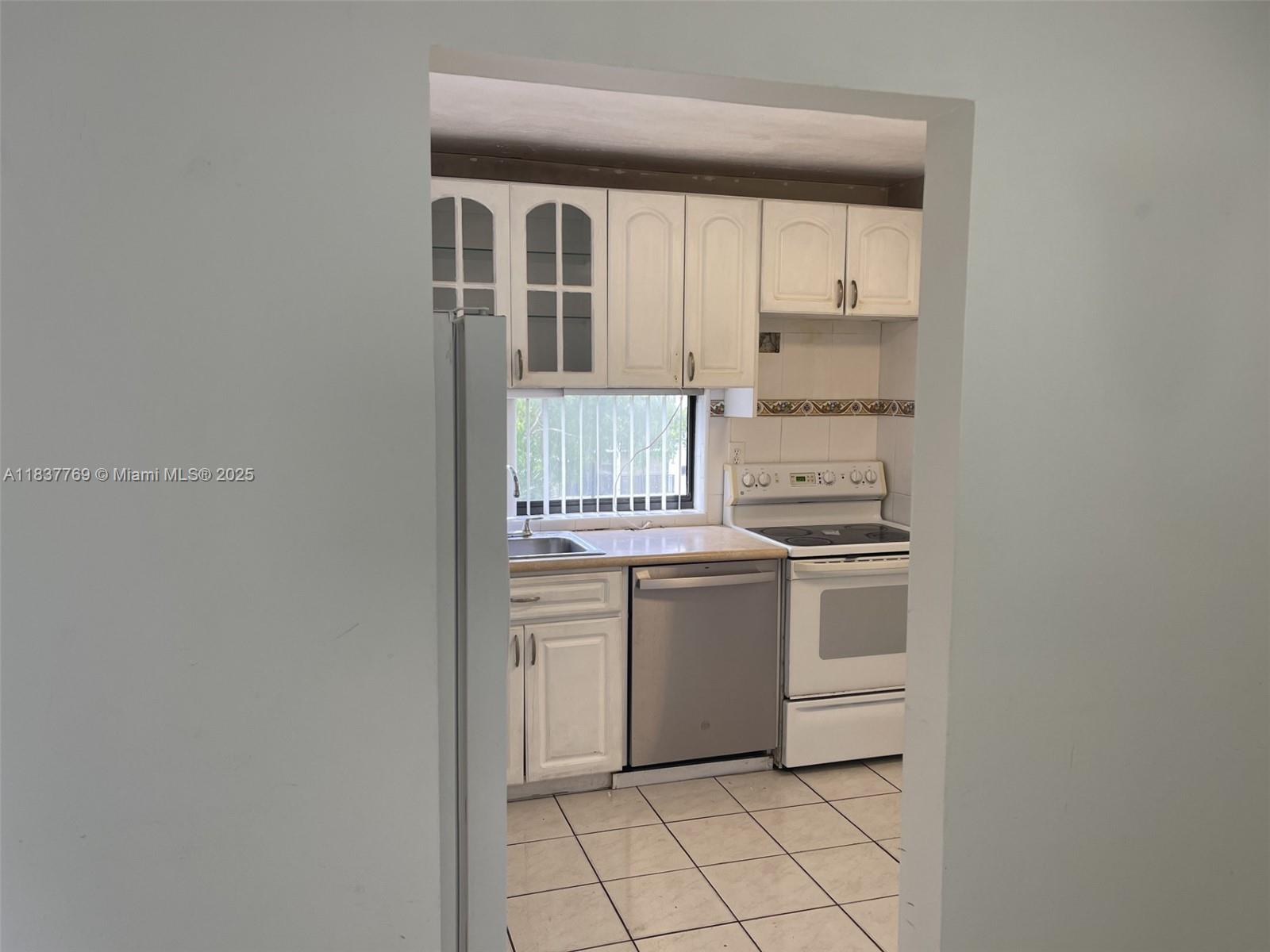 17011 North Bay Road, Unit 406 Sunny Isles Beach, FL 33160 - Photo 3 of 12 a kitchen with granite countertop white cabinets and white appliances