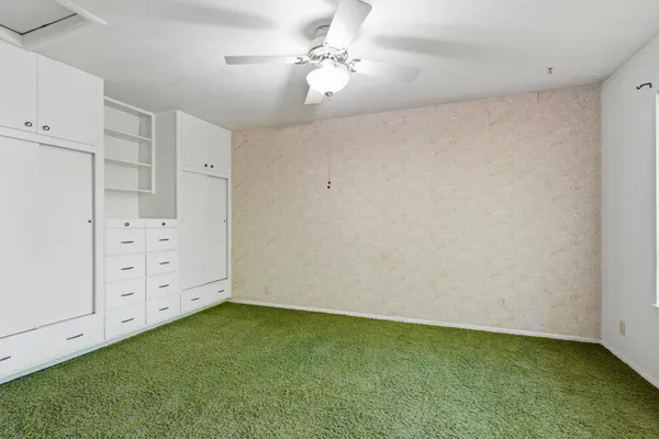 an empty room with cabinet and a chandelier fan