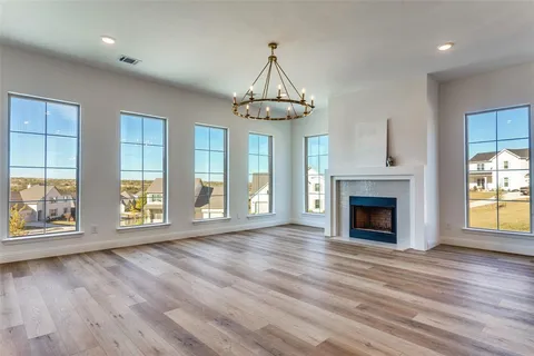 an empty room with wooden floor fireplace and windows