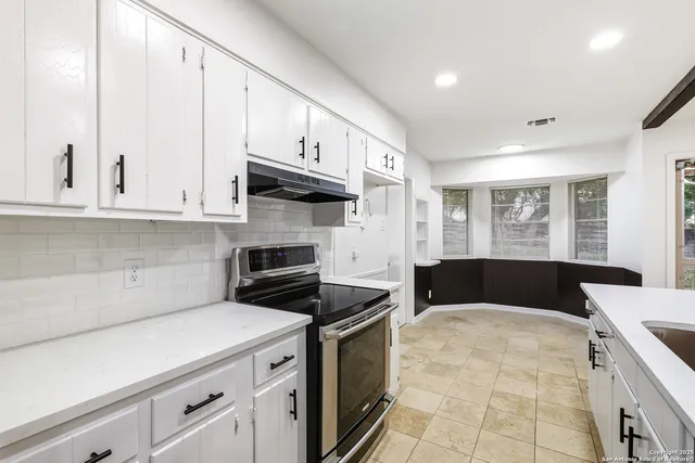 a kitchen with stainless steel appliances white cabinets and a stove top oven