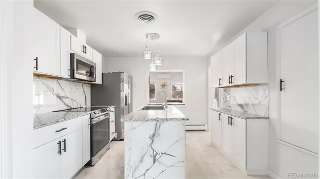 a kitchen with stainless steel appliances kitchen island granite countertop a refrigerator oven a sink dishwasher and white cabinets with wooden floor