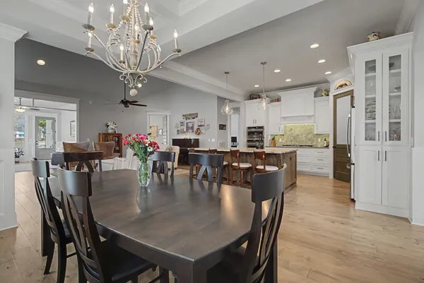 a dining room with stainless steel appliances furniture a chandelier and kitchen view