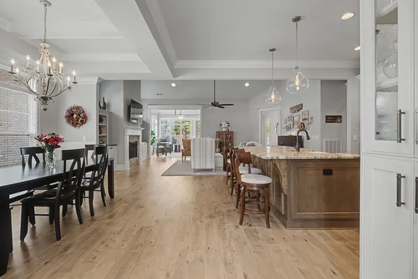 a dining room with wooden floor a chandelier a wooden table and chairs