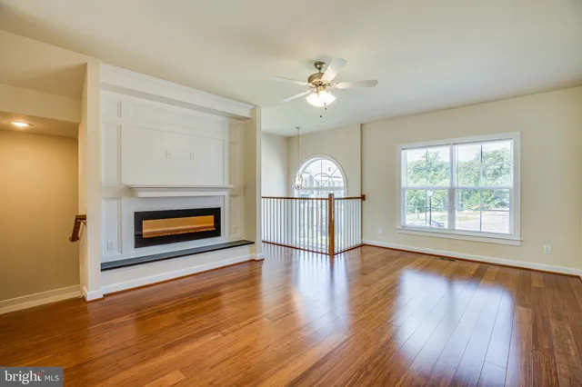 an empty room with wooden floor fireplace and windows