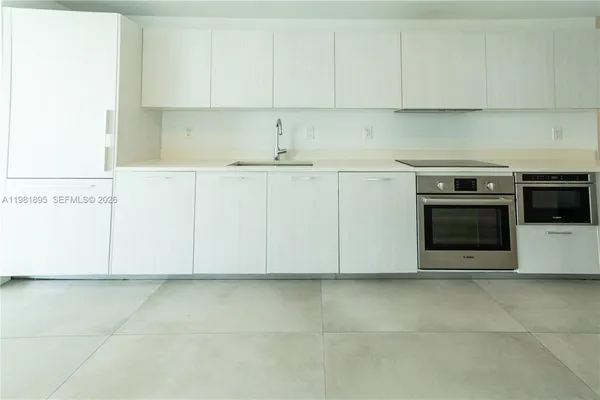 a view of kitchen with granite countertop white cabinets and stainless steel appliances