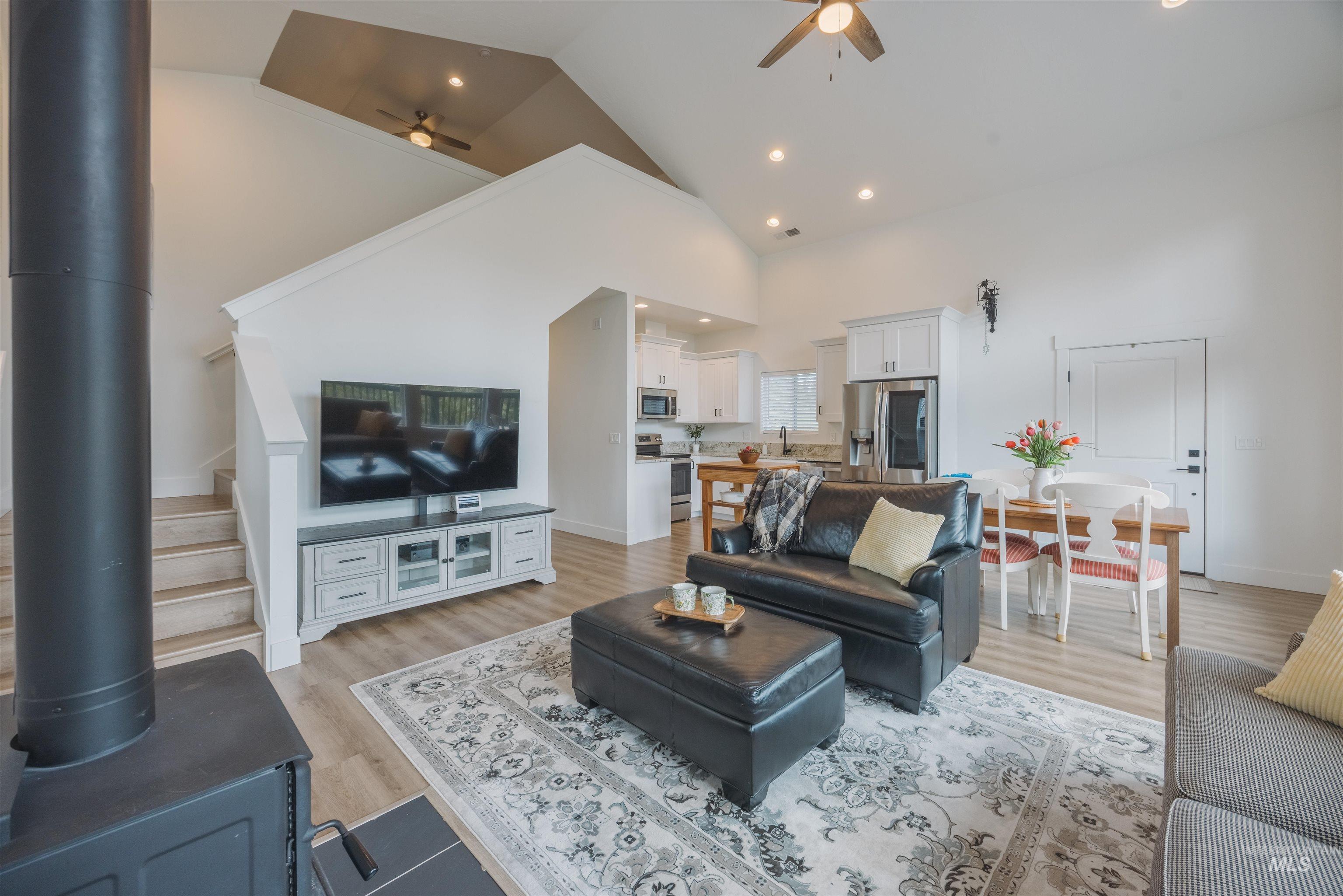 3873 Hot Springs Road New Meadows, ID 83654 - Photo 3 of 25 Open-concept living area featuring a wood-burning stove, vaulted ceilings, recessed lighting, wood-finish flooring, and a staircase with white railings