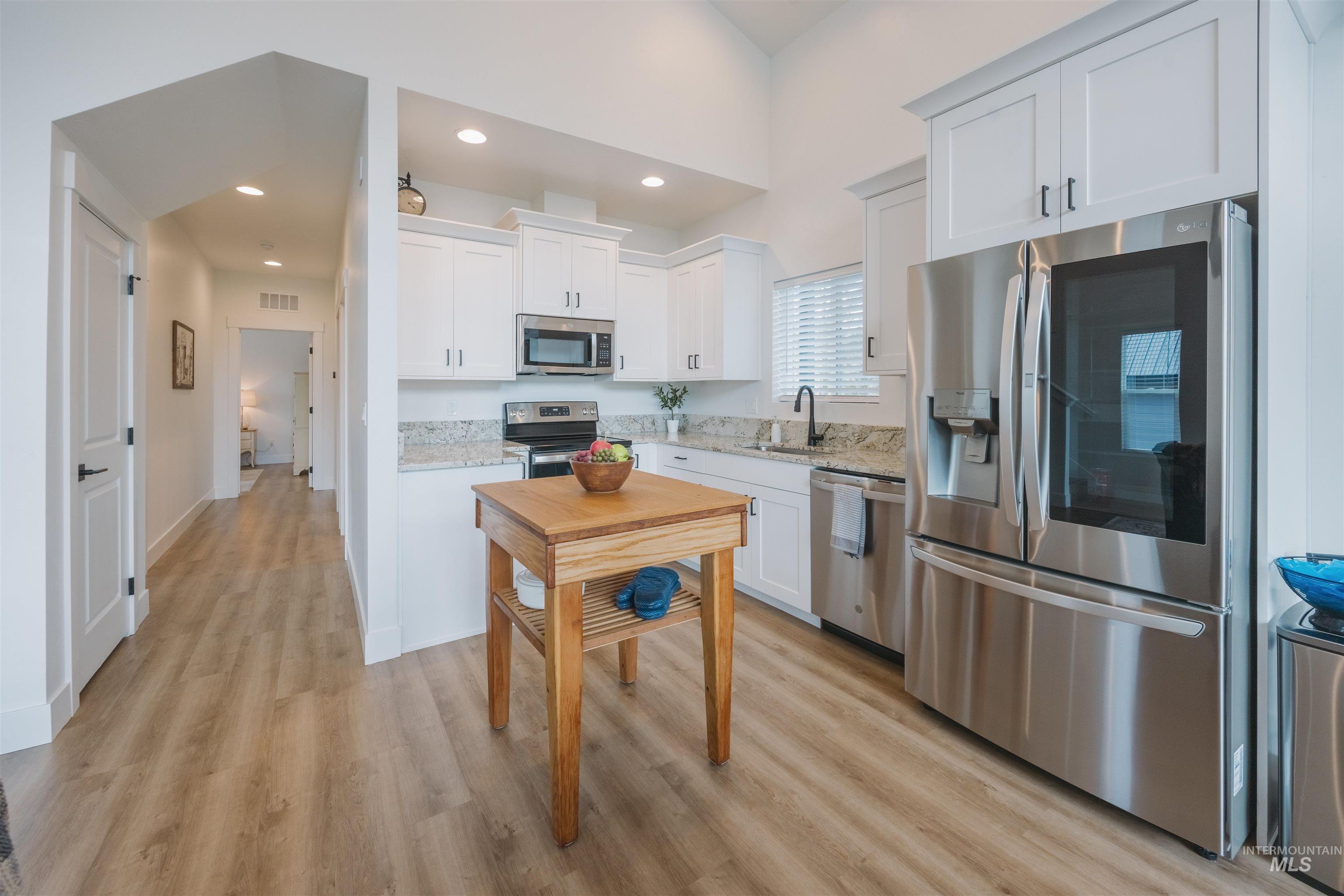3873 Hot Springs Road New Meadows, ID 83654 - Photo 5 of 25 Contemporary kitchen featuring white cabinetry, stainless steel appliances, light-toned wood-finish flooring, recessed lighting, and a granite countertop