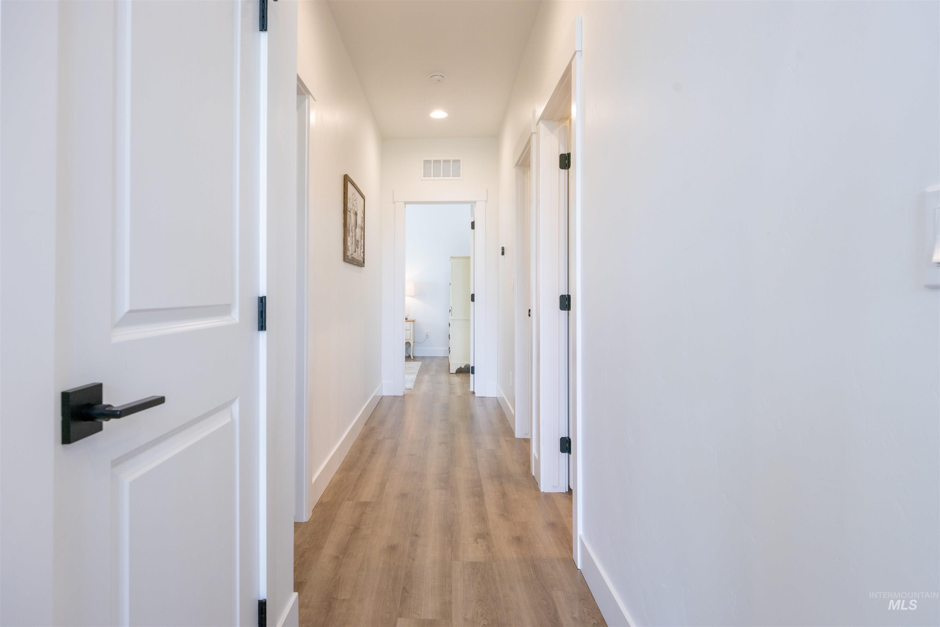 3873 Hot Springs Road New Meadows, ID 83654 - Photo 6 of 25 Interior hallway featuring wood-finish flooring, recessed lighting, white trim, and white paneled doors with matte black hardware