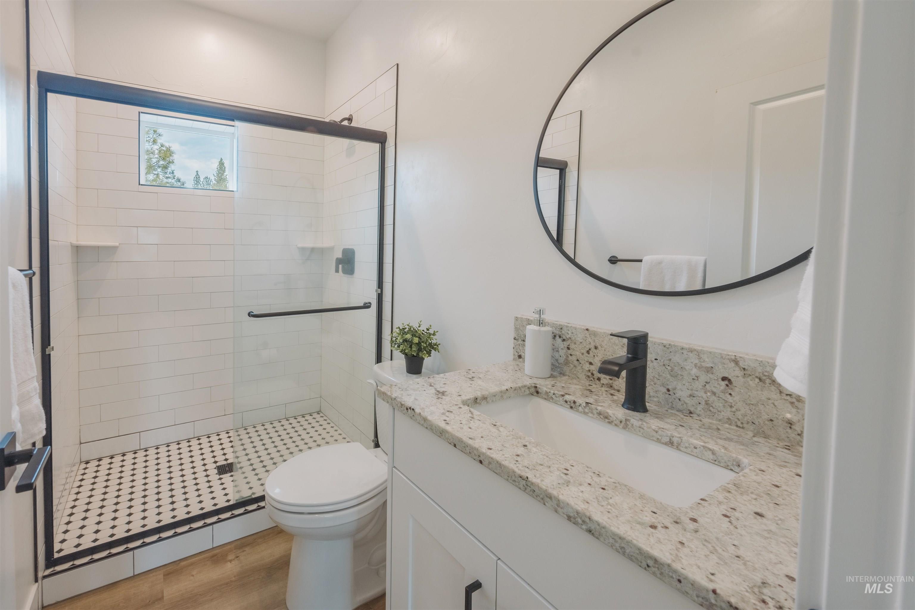 3873 Hot Springs Road New Meadows, ID 83654 - Photo 8 of 25 Modern bathroom featuring a glass-enclosed shower with white subway tile, black and white mosaic shower floor, and a rectangular window