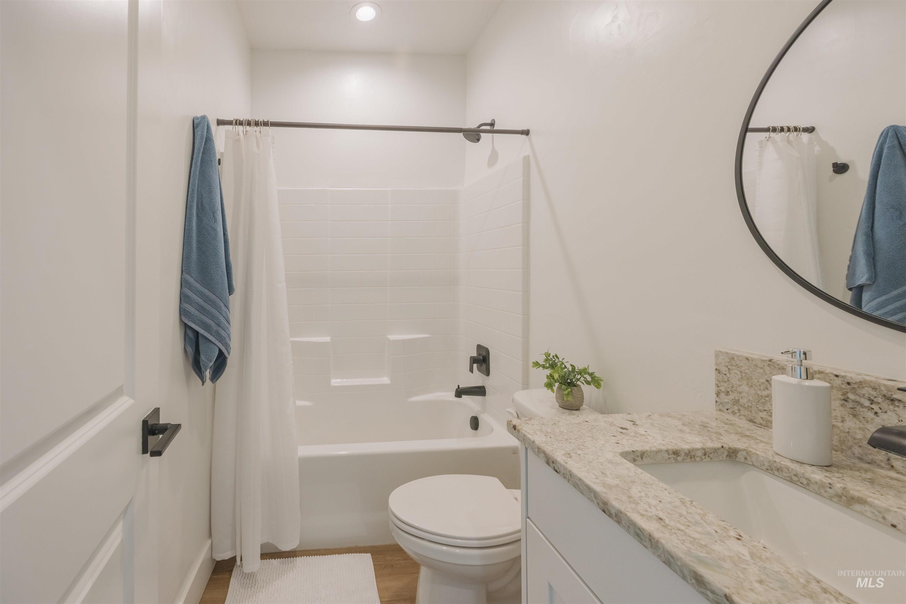 3873 Hot Springs Road New Meadows, ID 83654 - Photo 10 of 25 White bathroom featuring a built-in tub with shower, white vanity cabinet, light-toned countertop, and a round wall mirror
