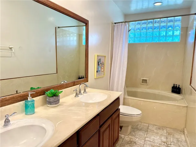 a bathroom with a granite countertop sink a toilet and shower