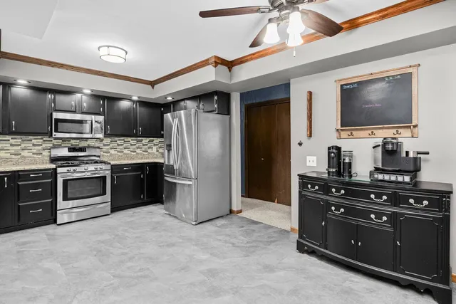 a kitchen with stainless steel appliances kitchen island granite countertop a stove refrigerator and microwave