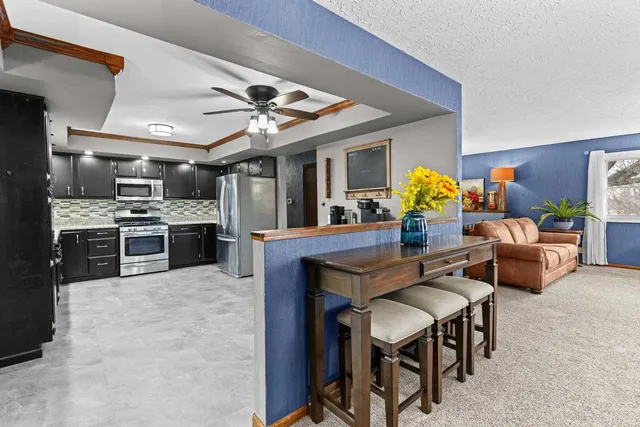a kitchen with stainless steel appliances kitchen island granite countertop a table chairs in it and wooden floors
