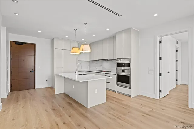 a large kitchen with stainless steel appliances a large counter top a stove and a refrigerator