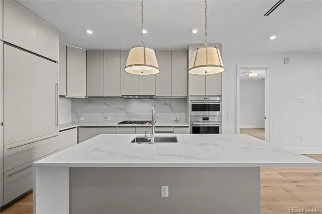 a kitchen with kitchen island granite countertop a sink a stove and a refrigerator