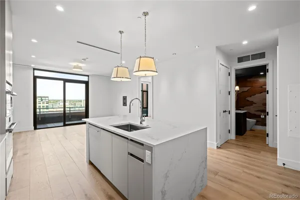 a kitchen that has a lot of cabinets a sink and wooden floor