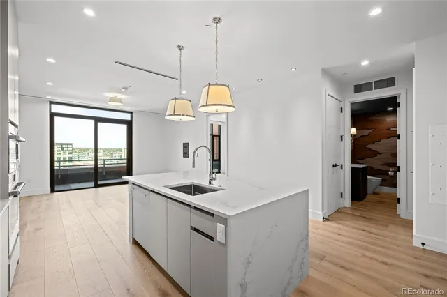 a kitchen that has a lot of cabinets a sink and wooden floor