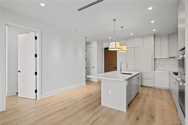 a large kitchen with stainless steel appliances granite countertop a sink stove and wooden floors