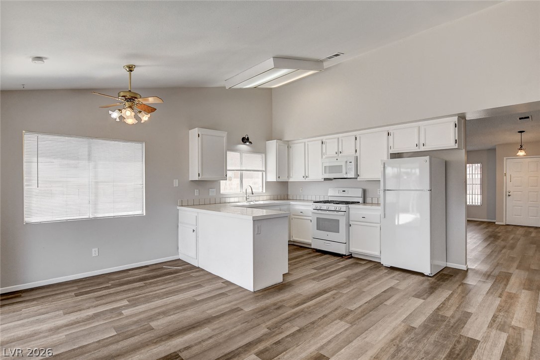 6209 Warm River Road Las Vegas, NV 89108 - Photo 11 of 39 An airy kitchen features abundant cabinetry, a practical layout, and seamless wood-look flooring.